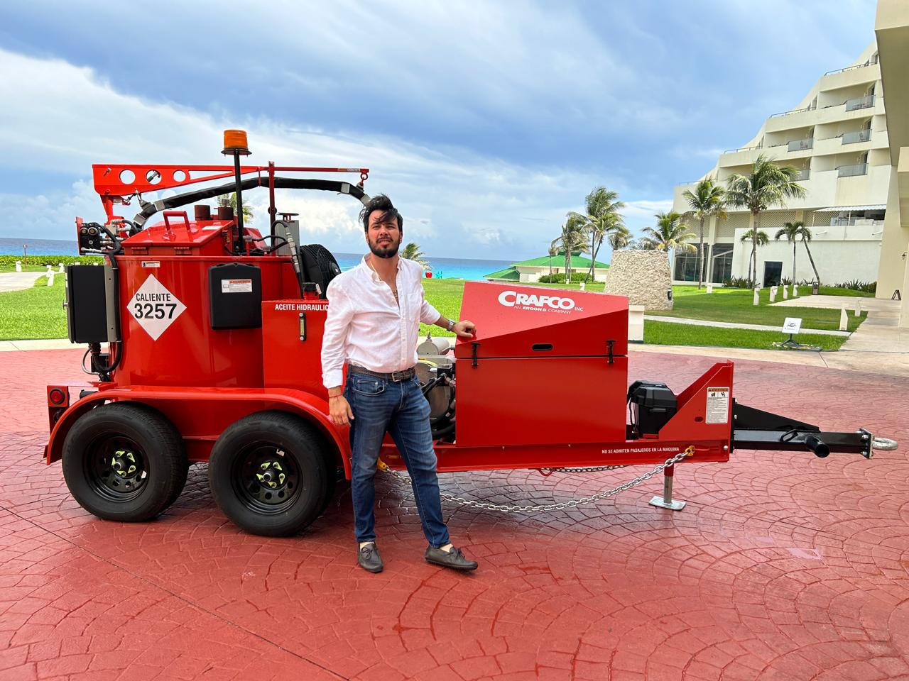 Hassan López junto a una selladora de grietas Crafco en un evento técnico